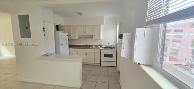 a kitchen with a refrigerator a stove top oven and white cabinets