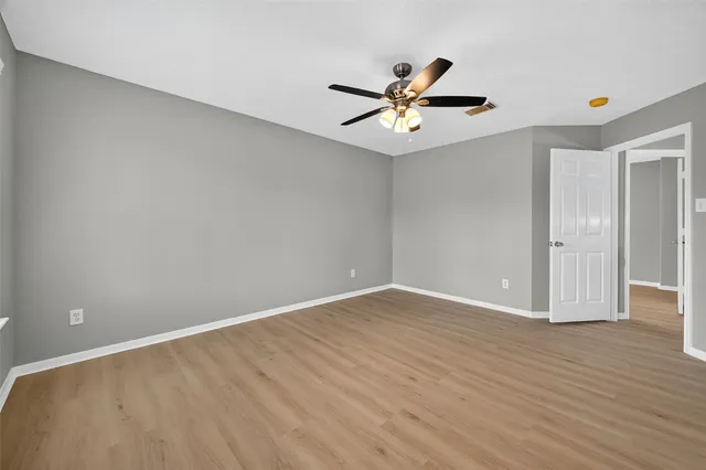 a view of an empty room with a window and wooden floor