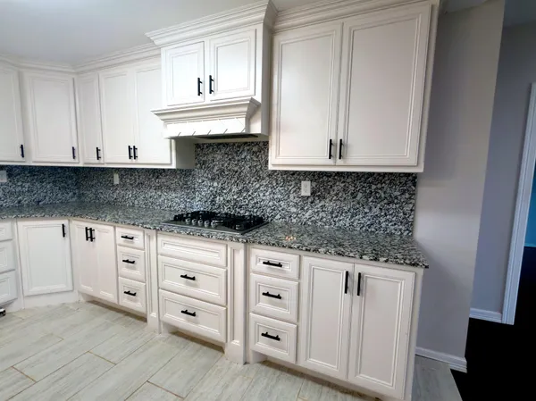 a kitchen with white cabinets and sink