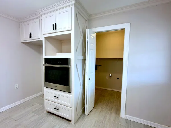 a view of an empty room with cabinet and wooden floor