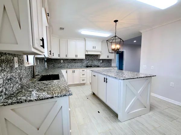 a kitchen with granite countertop a sink cabinets and wooden floor