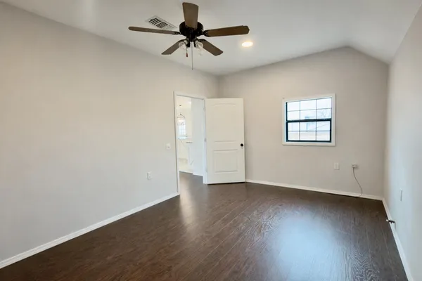 an empty room with wooden floor ceiling fan and windows
