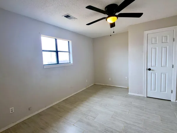an empty room with ceiling fan and window