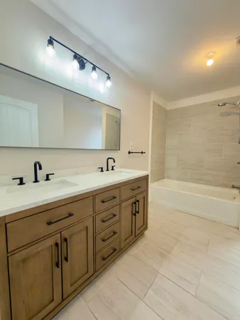 a spacious bathroom with a double vanity sink a mirror and a bathtub