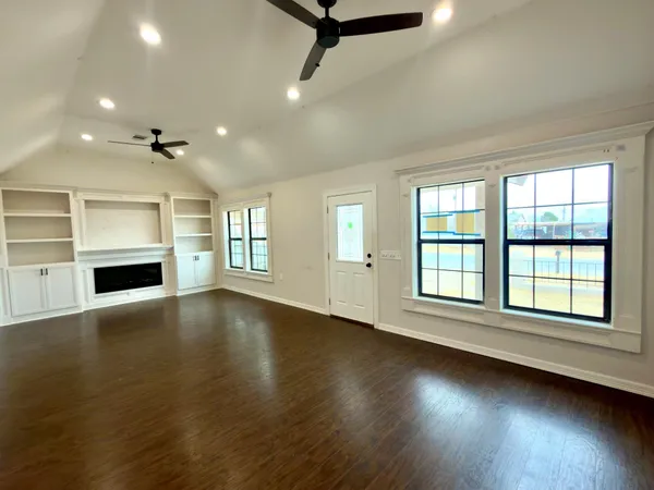 an empty room with windows and fireplace