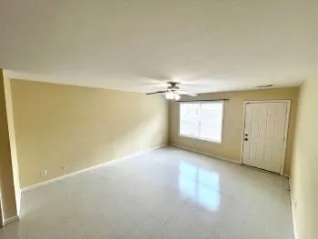an empty room with windows and fan