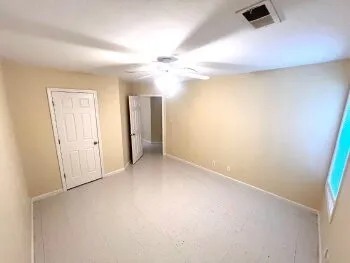 an empty room with windows and fan