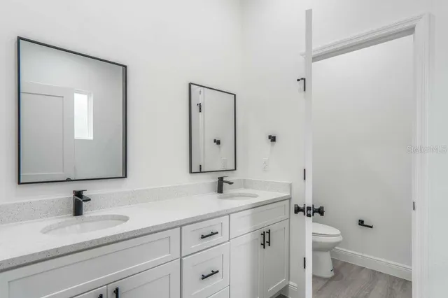 a bathroom with a granite countertop sink a toilet and a mirror