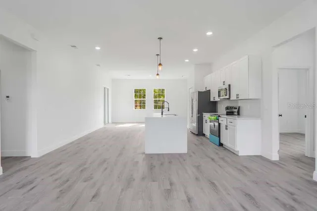a living room with stainless steel appliances kitchen island hardwood floor and a window