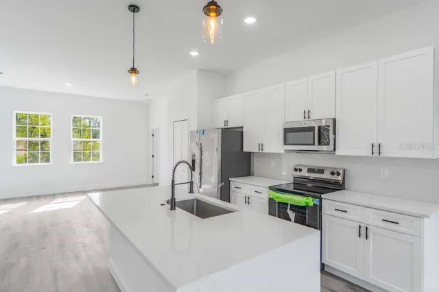 a kitchen with stainless steel appliances granite countertop a sink a stove and a refrigerator