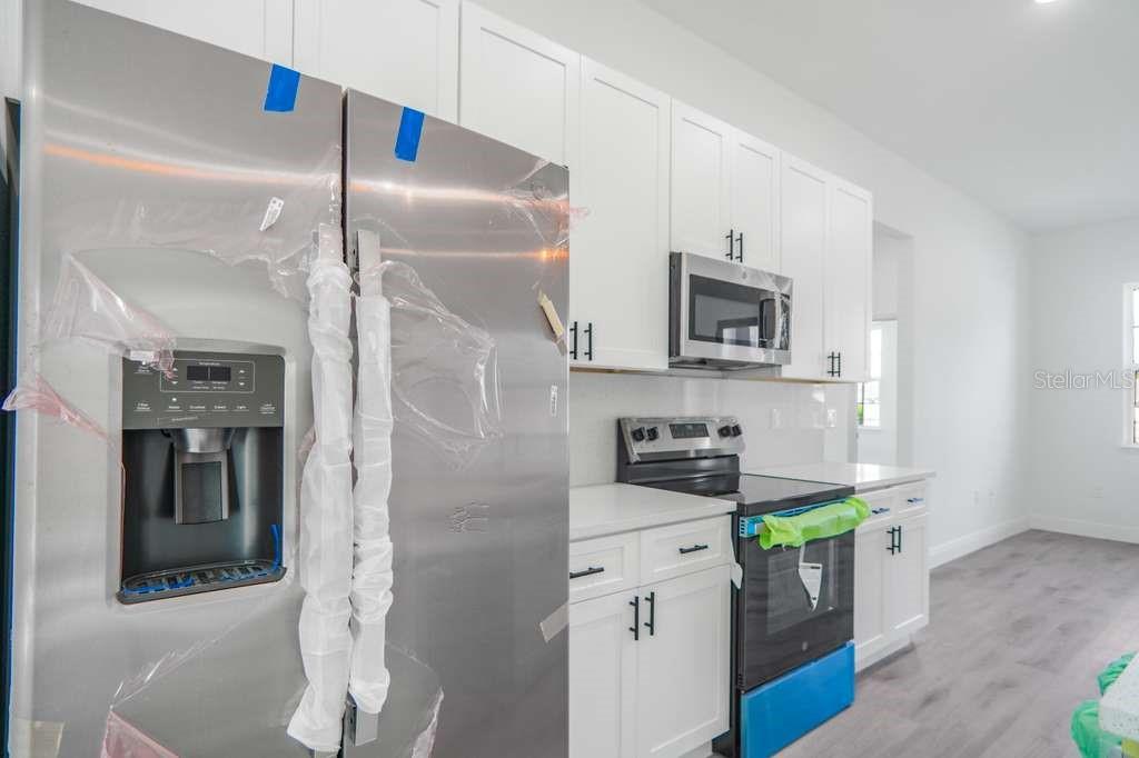 15683 Southwest 49th Avenue Road Ocala, FL 34473 - Photo 8 of 27 a kitchen with stainless steel appliances granite countertop a refrigerator a stove and a sink