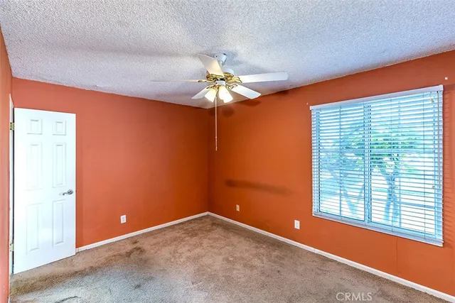 an empty room with a chandelier fan and windows