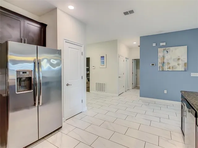 a view of a refrigerator in kitchen and an empty room