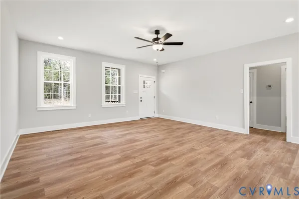a view of an empty room with a window and wooden floor