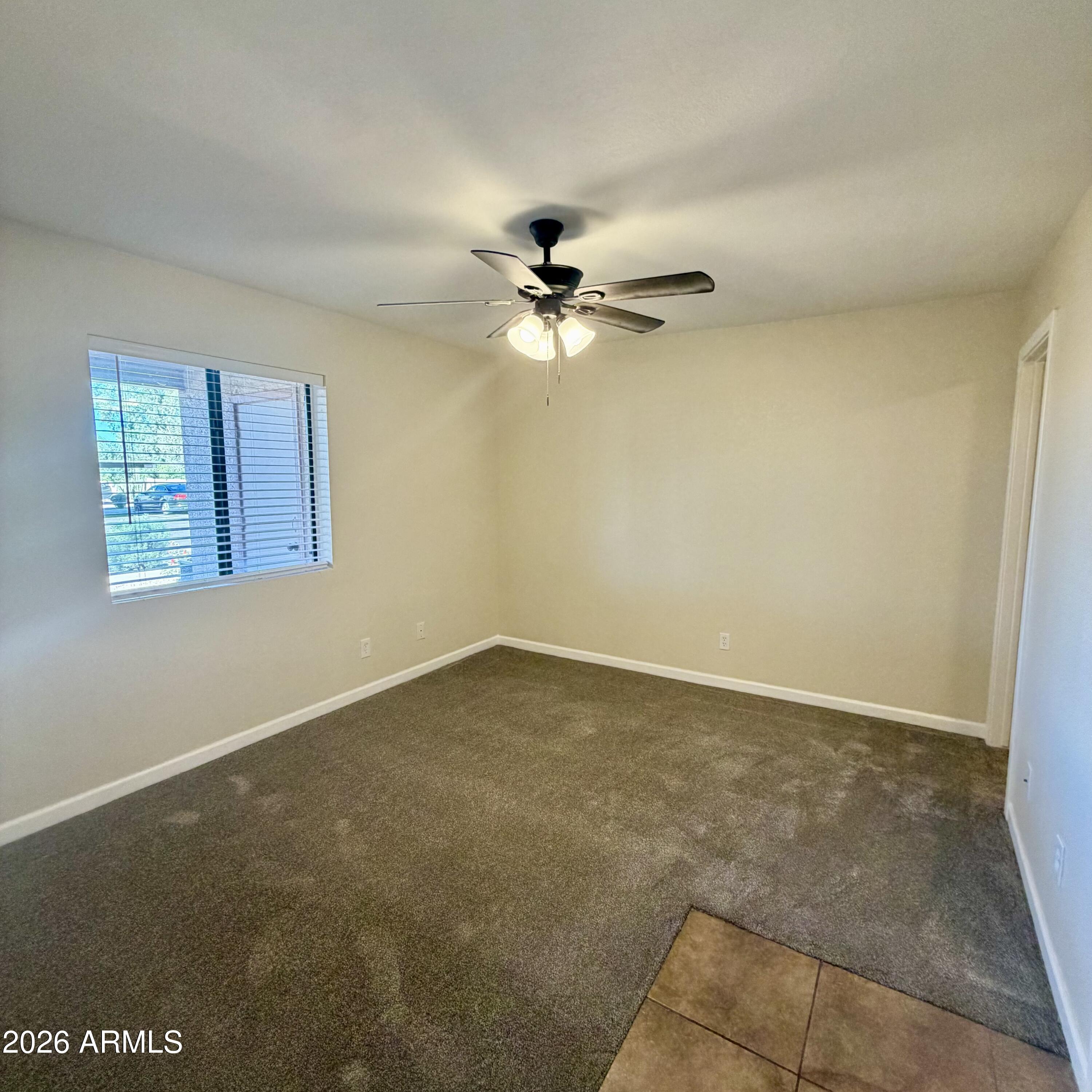 1440 North Idaho Road, Unit 1024 Apache Junction, AZ 85119 - Photo 4 of 9 an empty room with a window and a ceiling fan