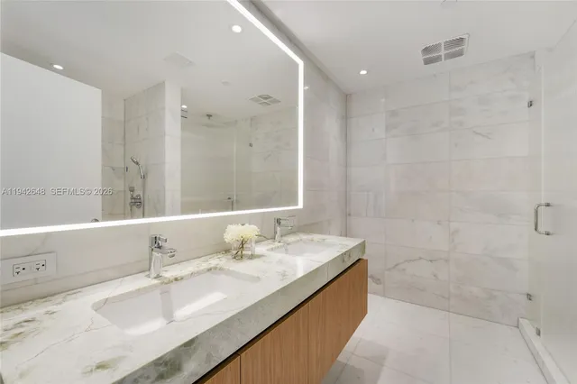 a bathroom with a granite countertop double vanity sink a mirror and a bathtub