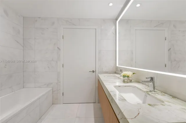 a bathroom with a granite countertop sink and a bathtub