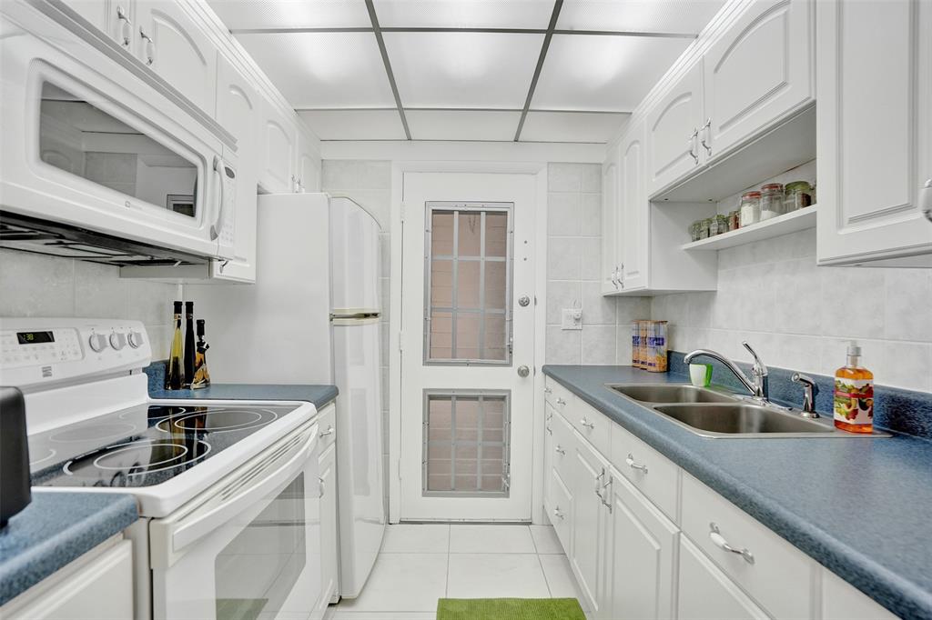 17001 Northeast 13th Avenue, Unit 104 Miami, FL 33162 - Photo 3 of 41 a kitchen with stainless steel appliances granite countertop a sink a stove and cabinets