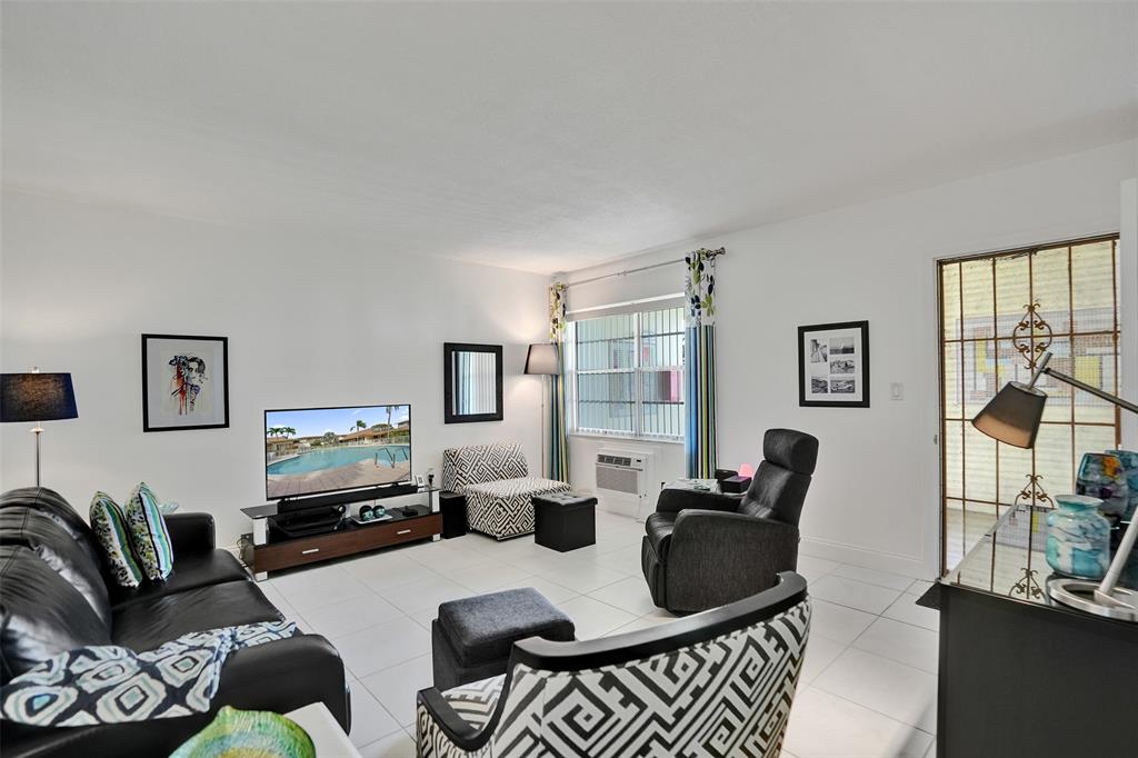 17001 Northeast 13th Avenue, Unit 104 Miami, FL 33162 - Photo 10 of 41 a living room with furniture a flat screen tv and a window