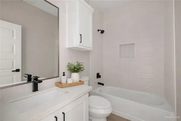 a bathroom with a granite countertop bathtub sink vanity mirror and toilet