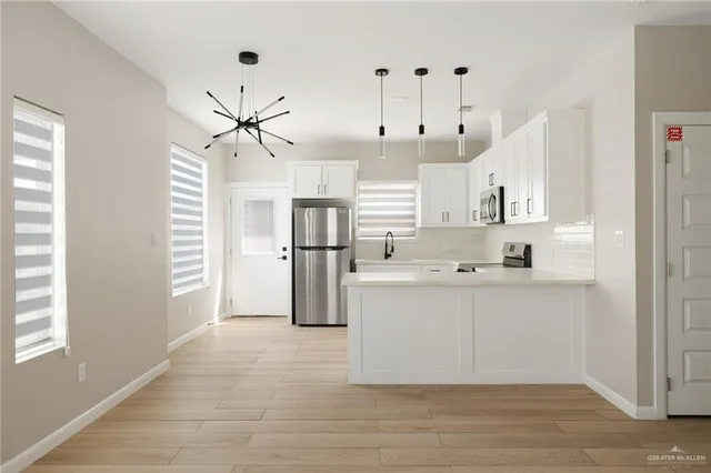 a view of kitchen with stainless steel appliances kitchen island refrigerator cabinets and wooden floor