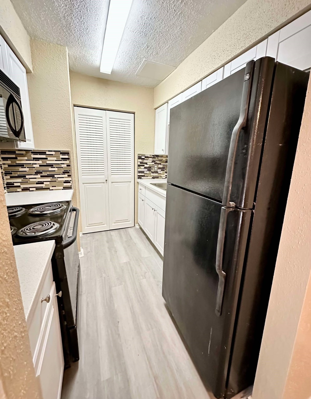 3630 Ocee Street Houston, TX 77063 - Photo 7 of 21 a kitchen with a refrigerator a stove and a wooden floor