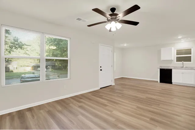 a view of an empty room with a window and a kitchen