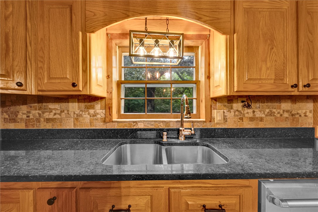 237 Spring Valley Road Liberty, SC 29657 - Photo 10 of 50 A well-lit kitchen features custom wood cabinetry and sleek granite countertops, complemented by a mosaic tile backsplash.