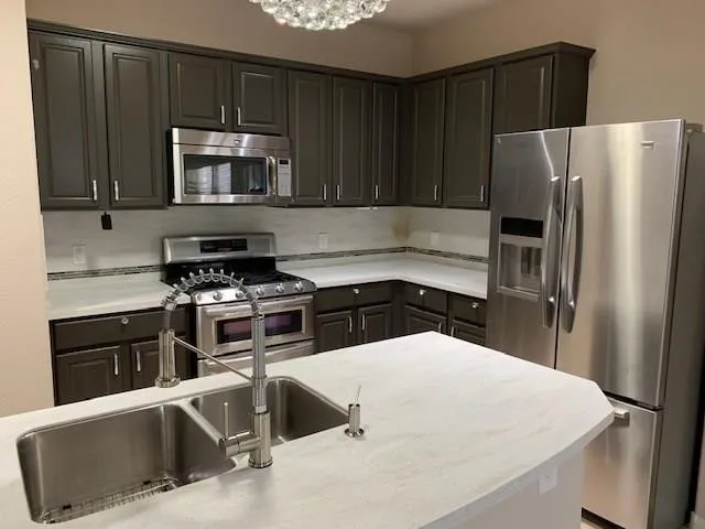 a kitchen with stainless steel appliances a refrigerator a stove a sink and a counter space