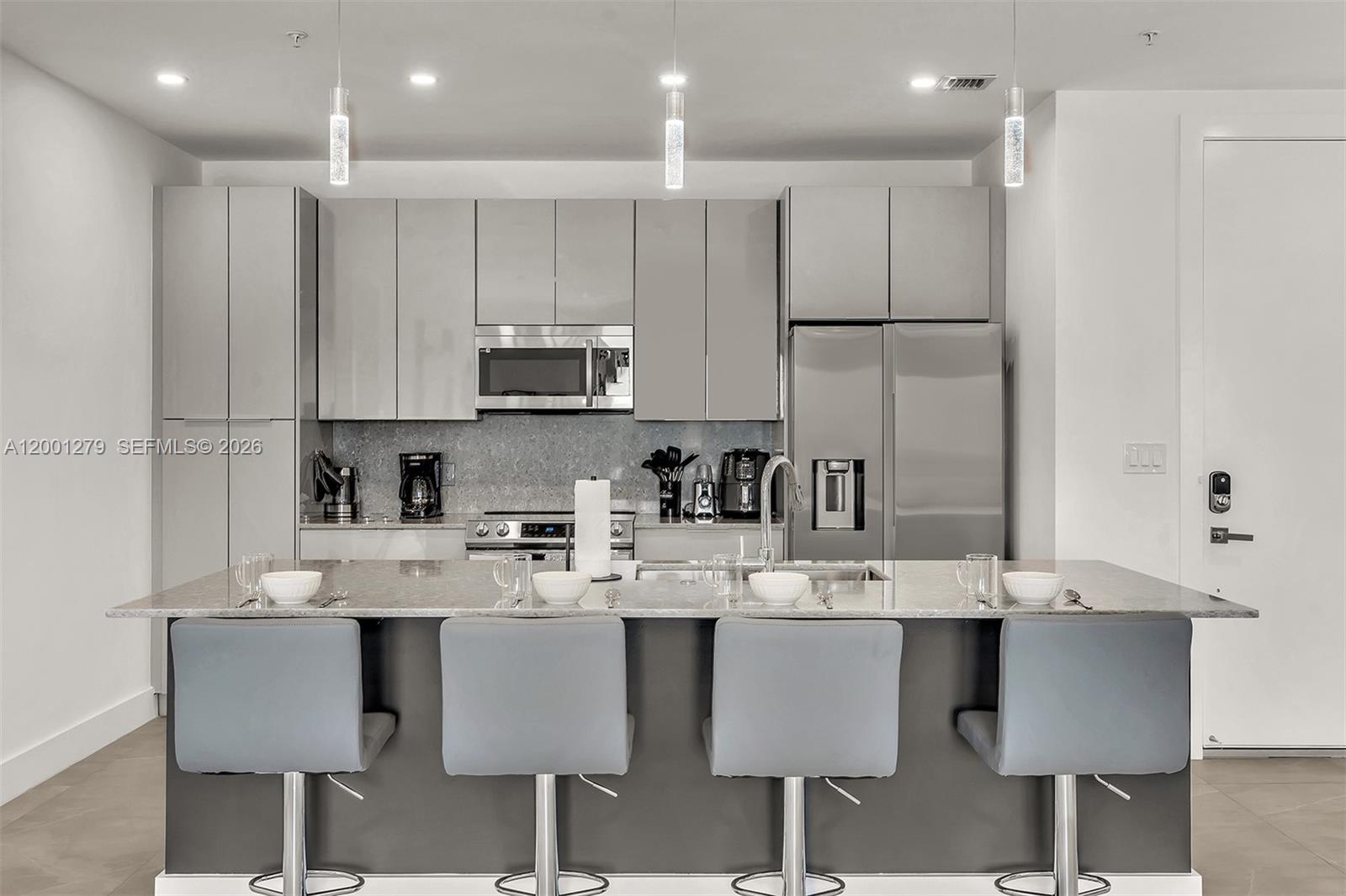 2100 Miami Road, Unit 403 Fort Lauderdale, FL 33316 - Photo 12 of 44 a kitchen with kitchen island granite countertop a sink and white cabinets