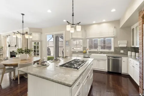 a kitchen with stainless steel appliances granite countertop a stove a sink dishwasher a dining table and chairs with wooden floor