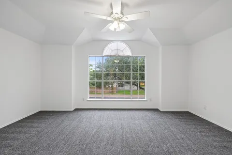 an empty room with a window and a fan