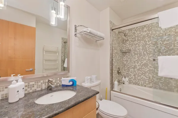 a bathroom with a granite countertop sink toilet a mirror and shower