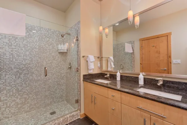 a bathroom with a granite countertop sink a mirror and shower