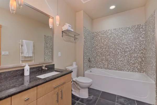 a bathroom with a granite countertop sink a toilet and shower
