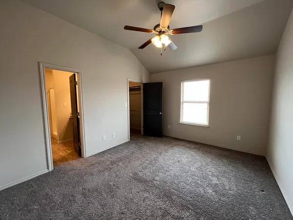 an empty room with chandelier fan and windows