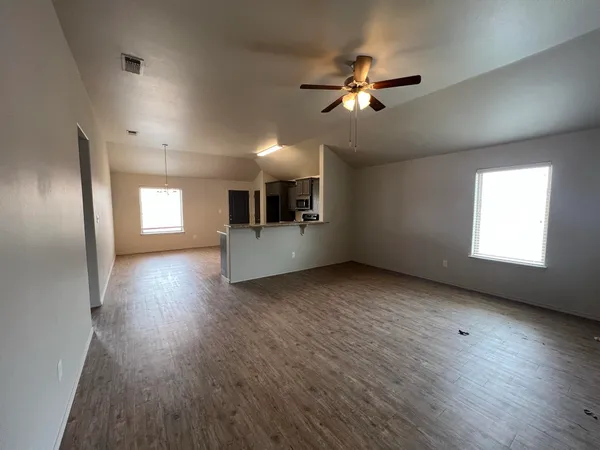 a view of empty room with wooden floor and window