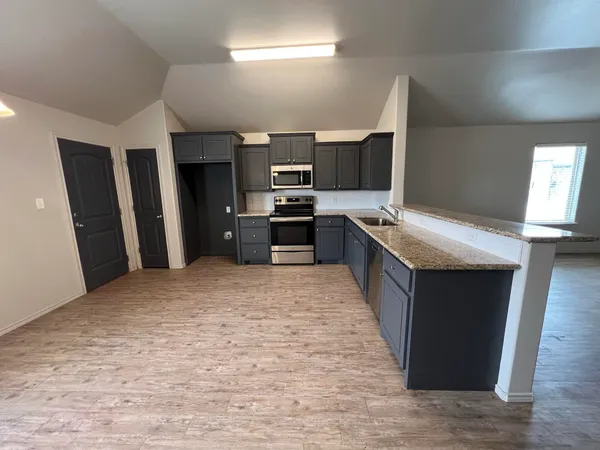 a large kitchen with stainless steel appliances granite countertop a sink stove and refrigerator