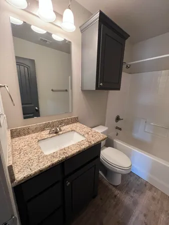 a bathroom with a granite countertop sink toilet and mirror