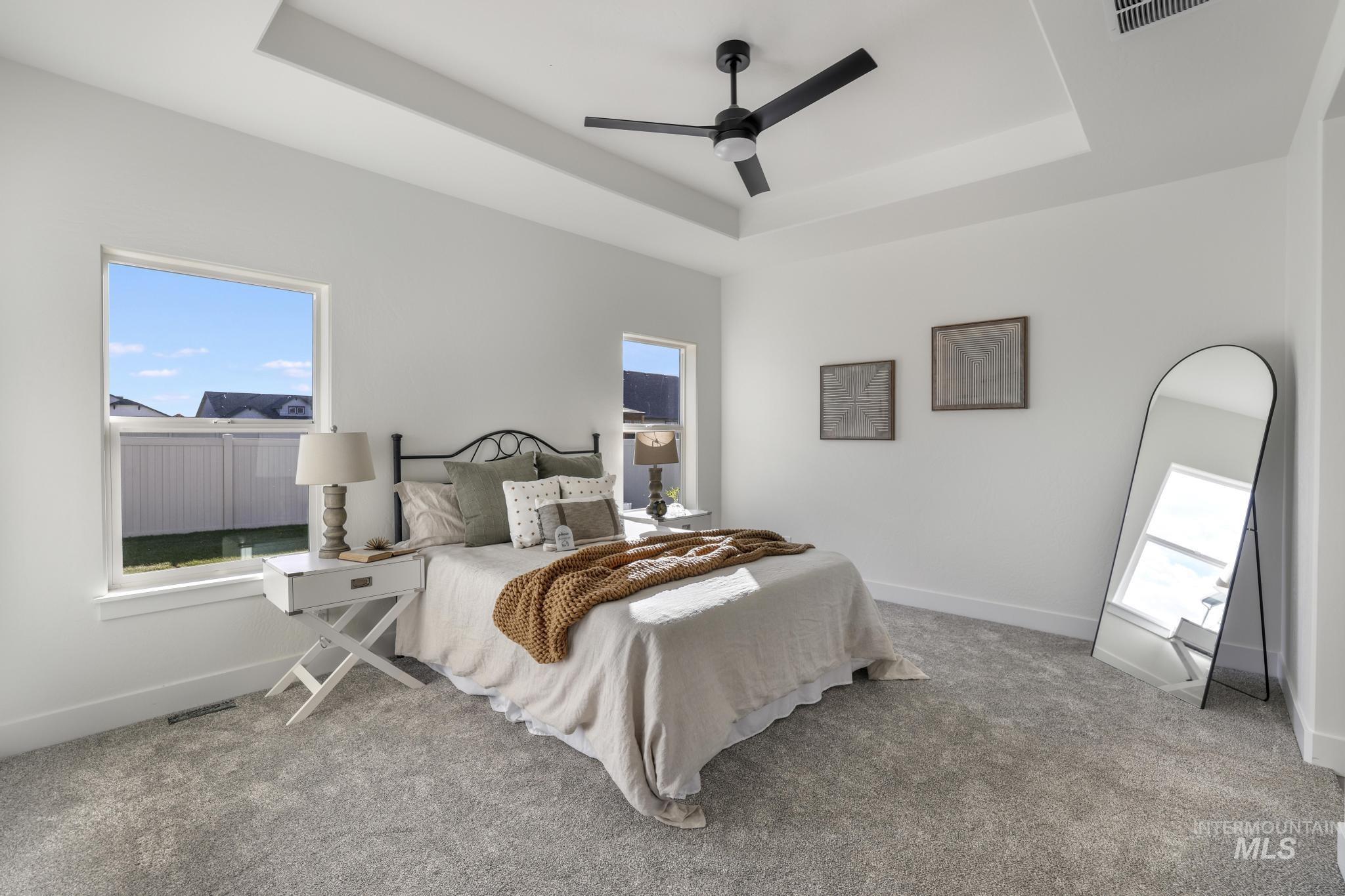 921 Adamite Road Kimberly, ID 83341 - Photo 13 of 25 Bedroom with a raised ceiling, multiple windows, light colored carpet, and ceiling fan
