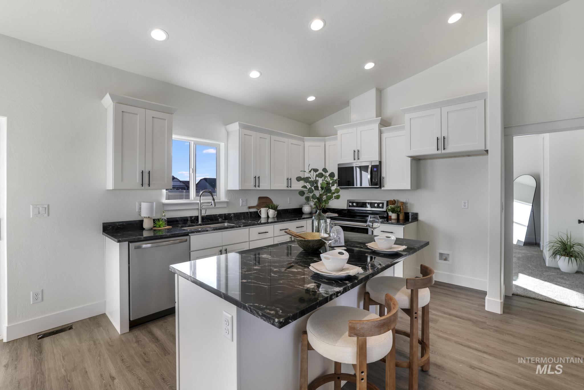 921 Adamite Road Kimberly, ID 83341 - Photo 3 of 25 Kitchen with dark stone countertops, white cabinetry, a kitchen island, a breakfast bar area, and light wood-type flooring