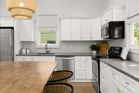 a kitchen with stainless steel appliances granite countertop a sink a stove a microwave a sink a refrigerator and cabinets