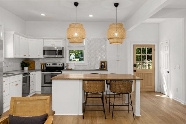 a kitchen with stainless steel appliances granite countertop a stove top oven a refrigerator a sink dishwasher a dining table and chairs with wooden floor
