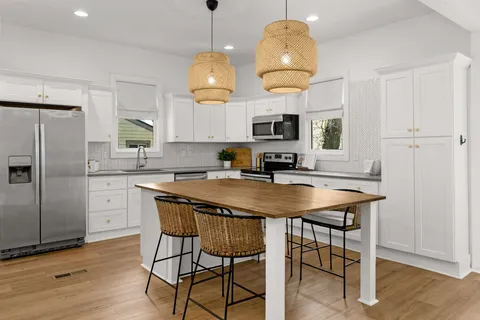 a kitchen with stainless steel appliances granite countertop a sink a stove a refrigerator and island with wooden floor