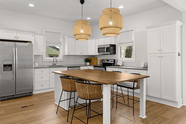 a kitchen with stainless steel appliances granite countertop a sink a stove a refrigerator and island with wooden floor