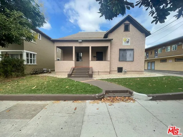 a front view of a house with a yard and potted plants