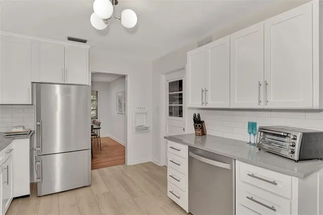 a kitchen with cabinets stainless steel appliances and wooden floor