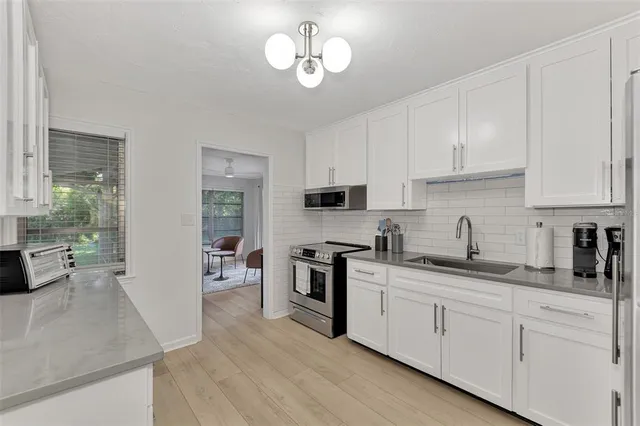 a kitchen with stainless steel appliances a stove a sink and white cabinets