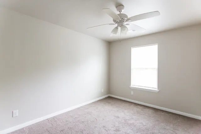 an empty room with a window and a fan