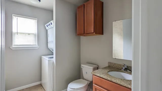 a bathroom with a granite countertop sink toilet and mirror
